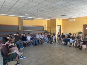 partecipanti in semicerchio segnano una lettera dell'alfabeto manuale